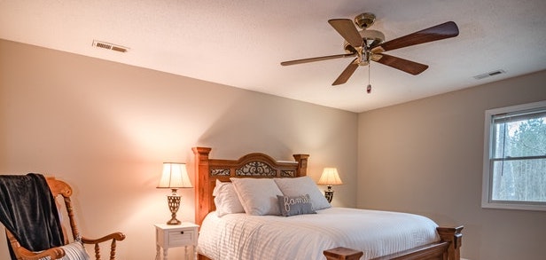 a well-lit bedroom with a ceiling fan