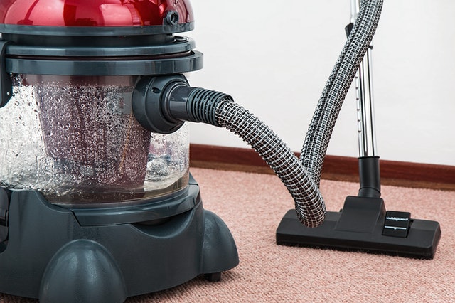 A vacuum with an attachment at work on a carpet 