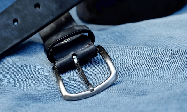 A belt laying on a pair of jeans
