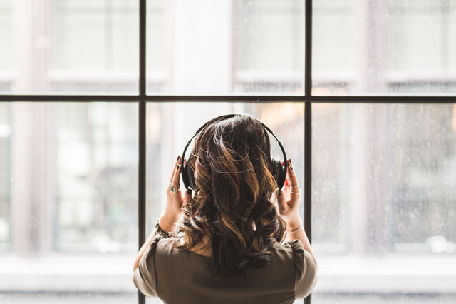 A girl listening to music on her headphones facing backwards