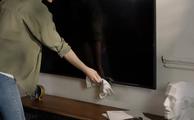 Woman cleaning a TV screen with a cloth