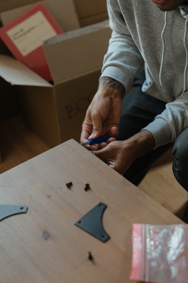 A pair of hands removing nuts and bolts from a table.