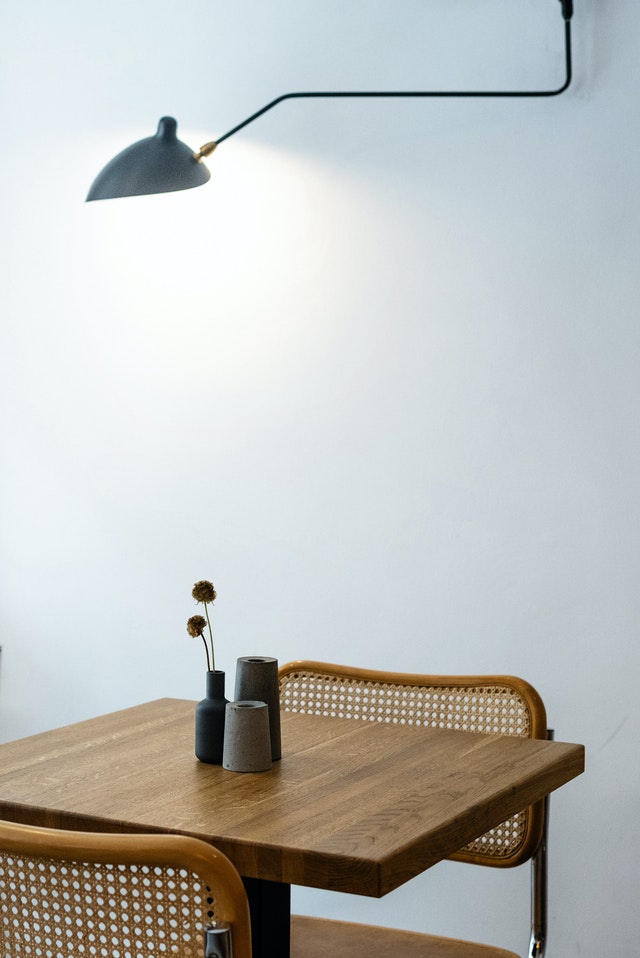 A modern light on a wooden table against a white wall