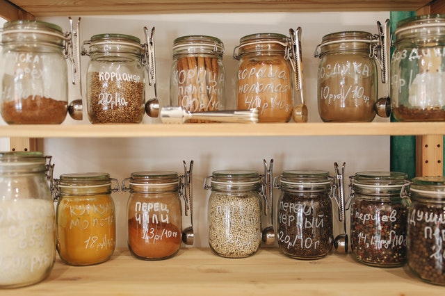 Glass jars filled with grains and spices in a pantry. 