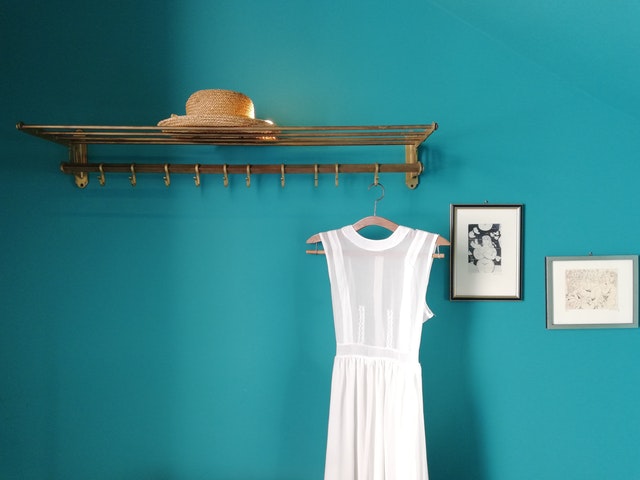 A blue wall with a white dress hanging in front of it