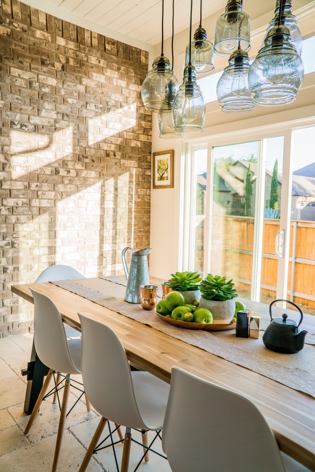 A bright dining room drenched in sunlight with succulents and a kettle on a wooden table