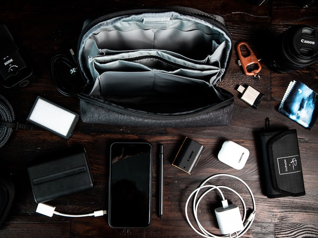 An overhead view of a work desk with a work bag and a few chargers and electronics. 