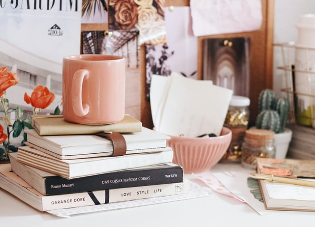 A coffee cup placed above a few books and diaries on a desk