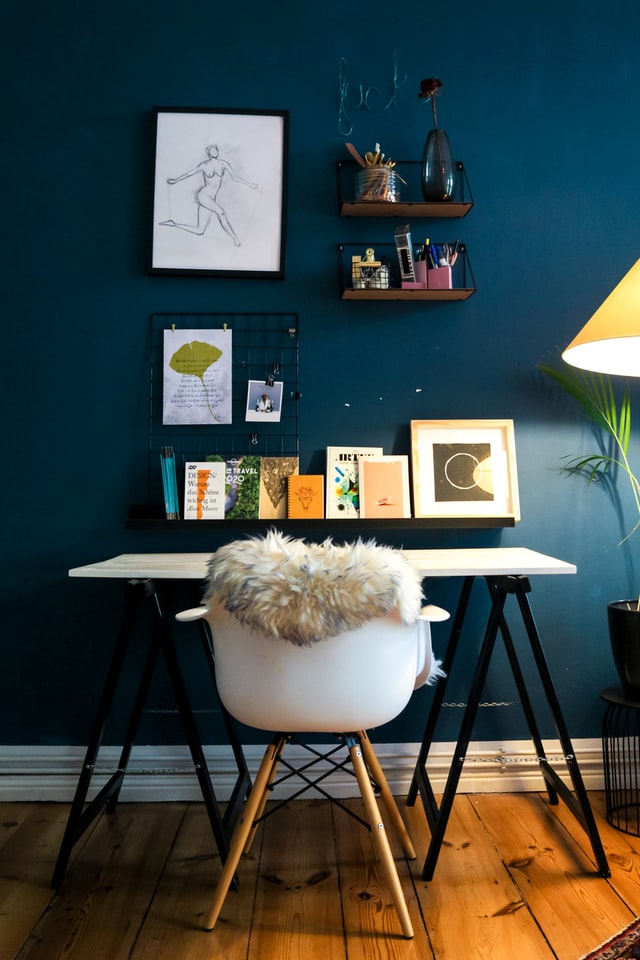 A deep blue wall with a desk in front of it
