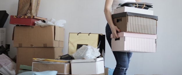 A girl carrying shoe boxes and clothes out of a frame.