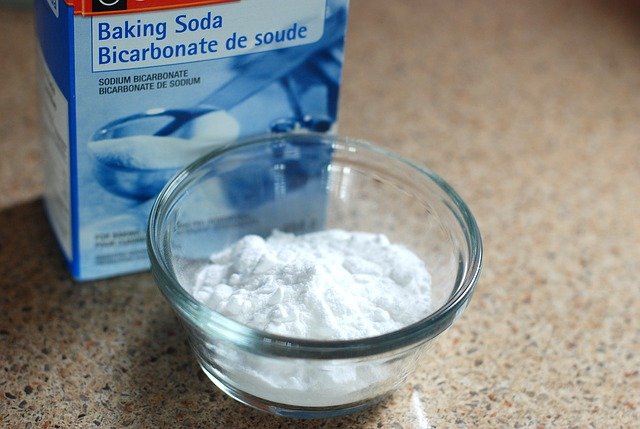 A box of baking soda and a glass bowl full of baking soda. 