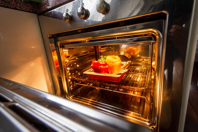 An open clean oven with food on a baking tray. 