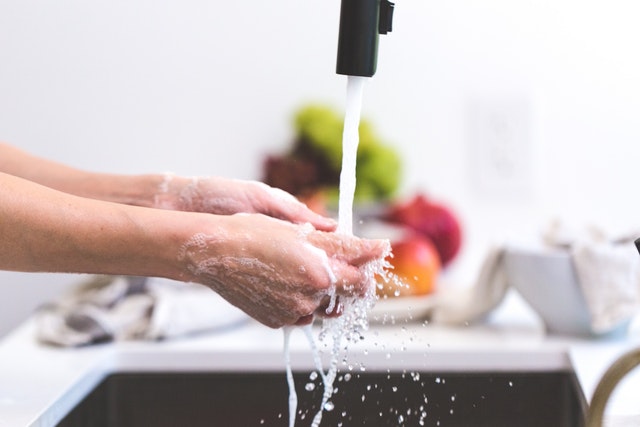 A pair of hands under a running kitchen faucet