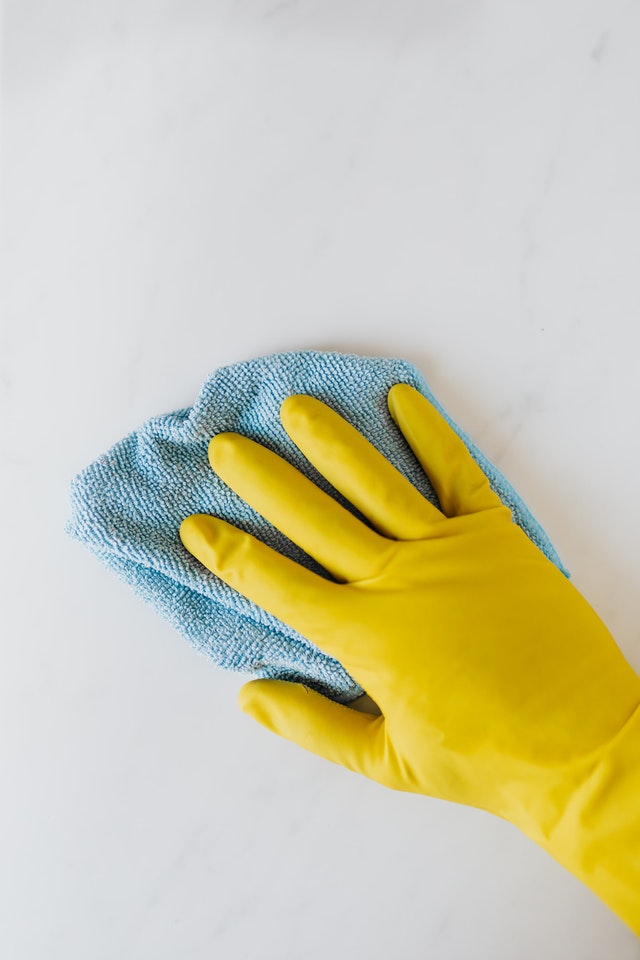 A hand in yellow rubber gloves with a cleaning cloth