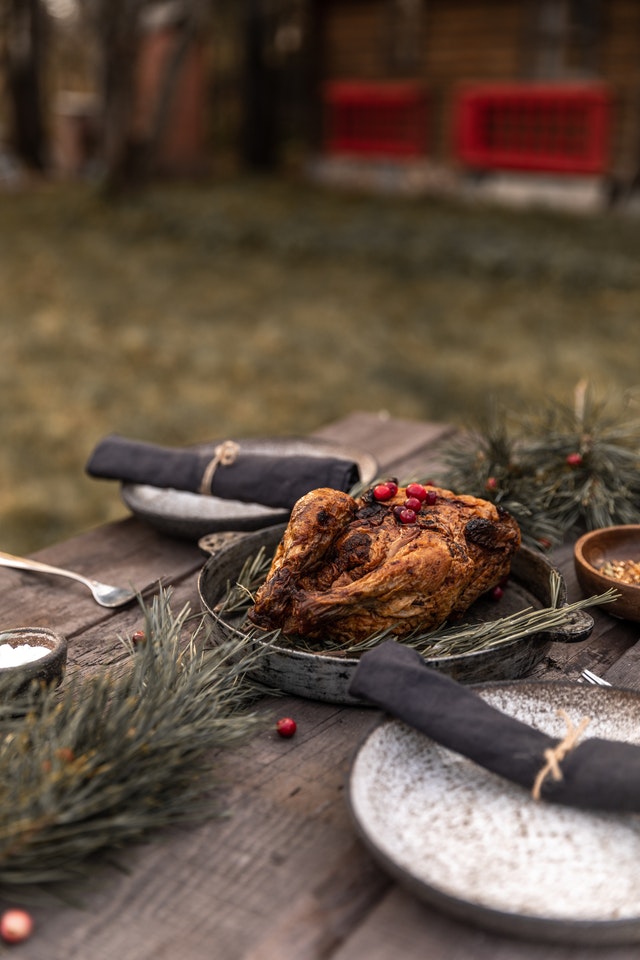 An outdoor table setting with a roasted turkey as a center piece 