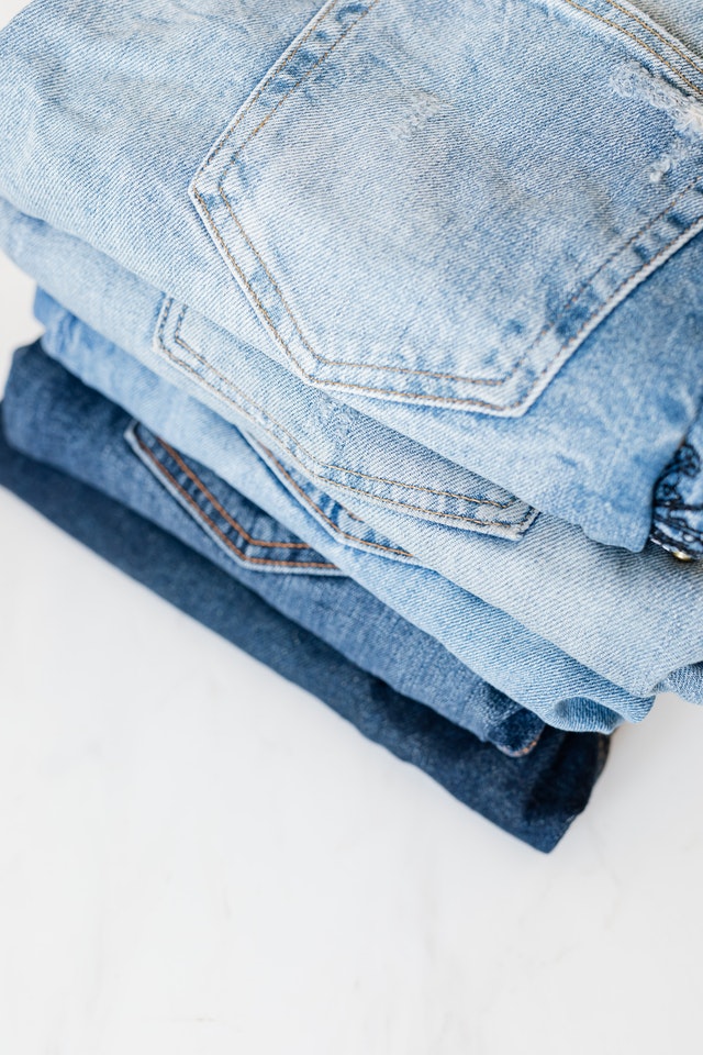 Five pairs of folded blue jeans.