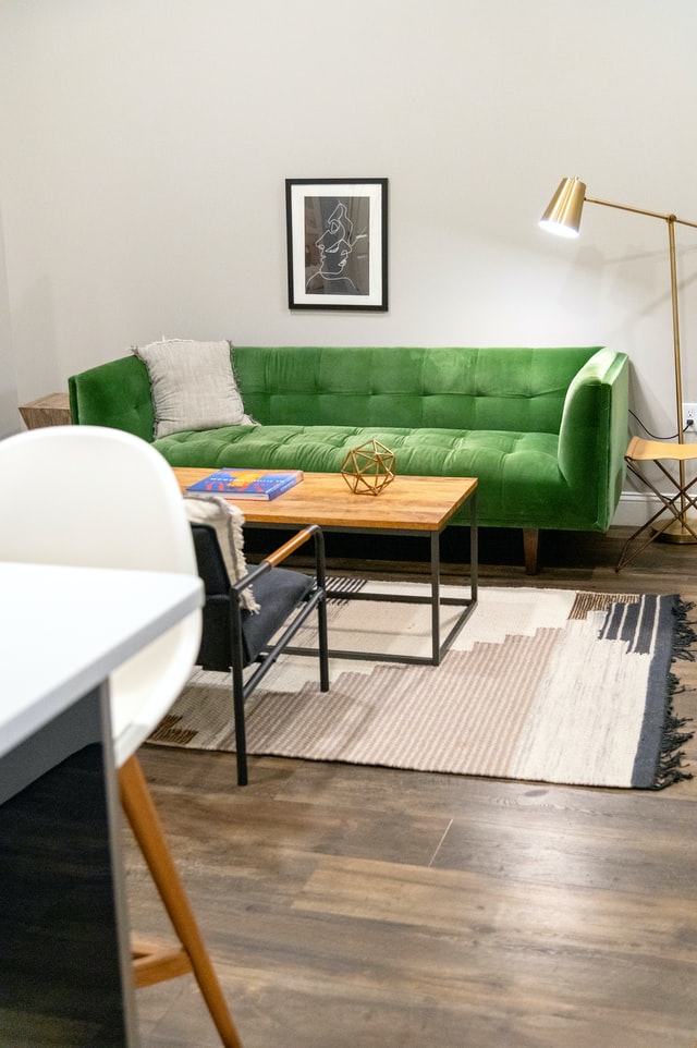 A clean shot of a living room with a green couch