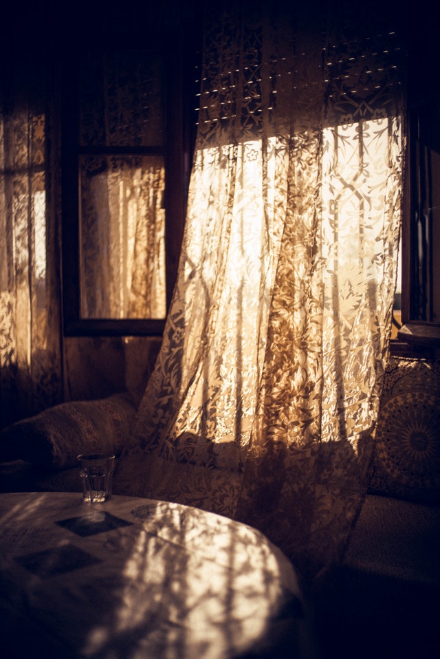 A white curtain lets in sunlights near a dinning area