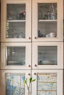 A cabinet with kitchen utensils and a plant