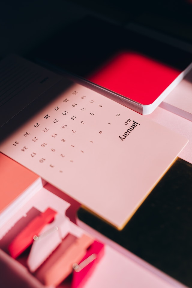 A pink calendar and a planner laying on a table.