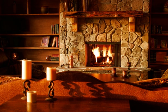 A warm comforting fireplace next to a shelf. 