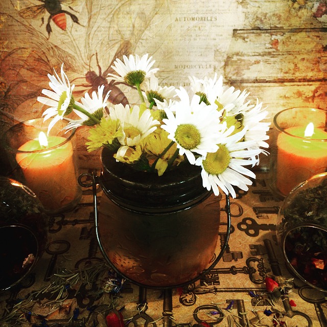 A bunch of white florals in a vase surrounded by candles. 