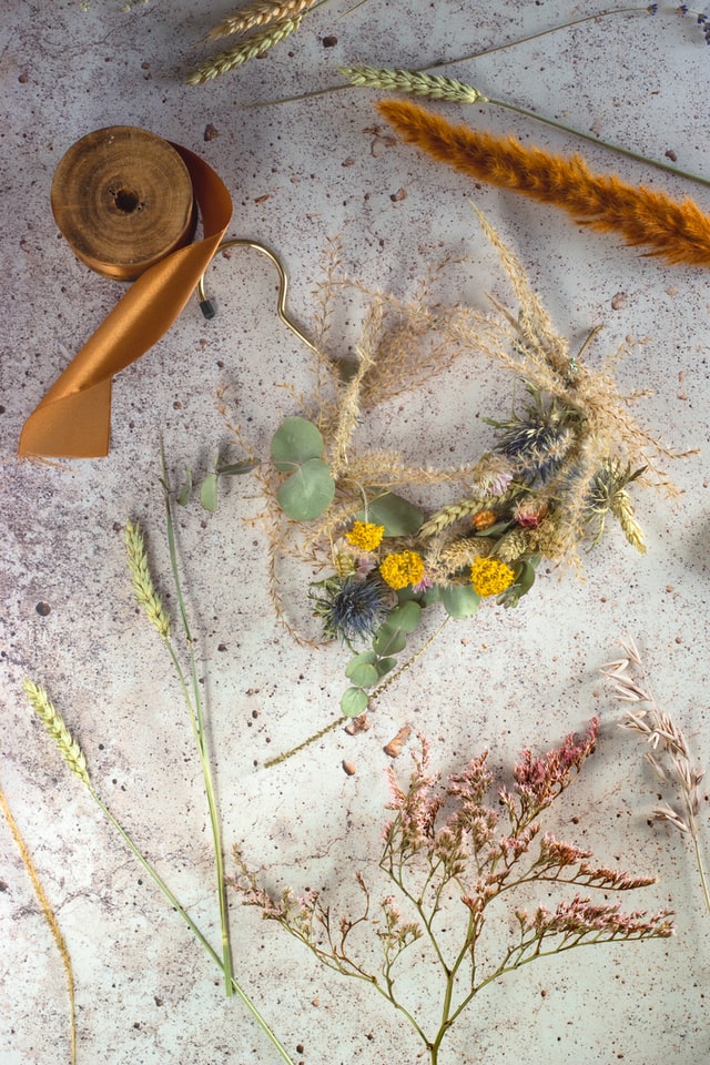 A bunch of dried flowers and ribbons against a plain background.