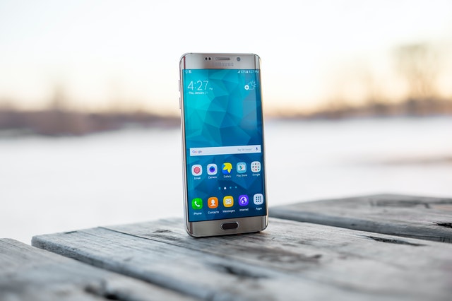 A phone screen sitting on a deck outdoor.