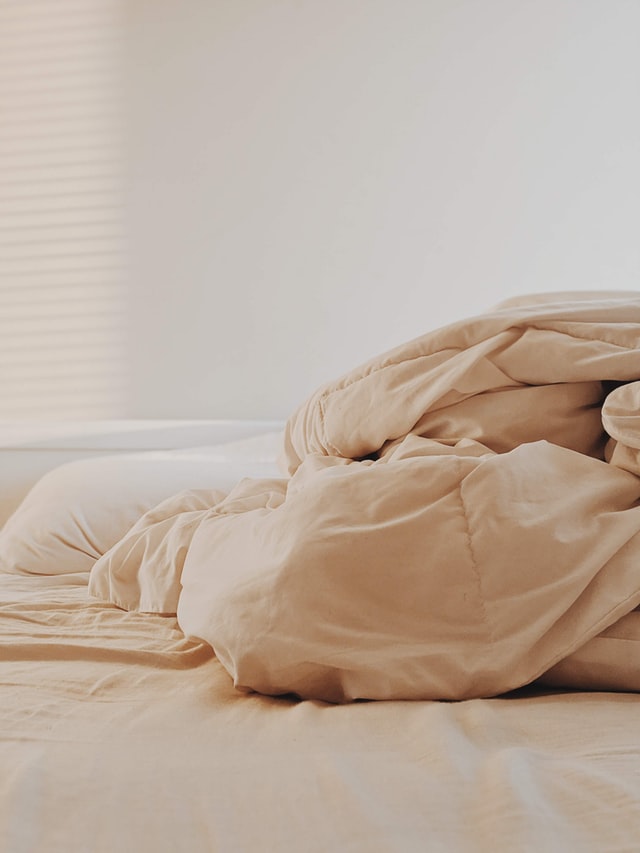 A big comforter scrunched up on a bed. 