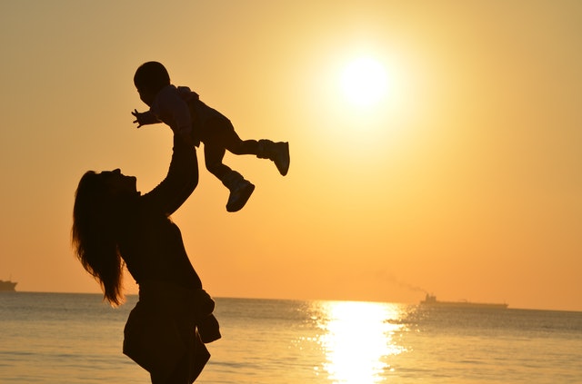 A child and a mom by a sunset near a ocean