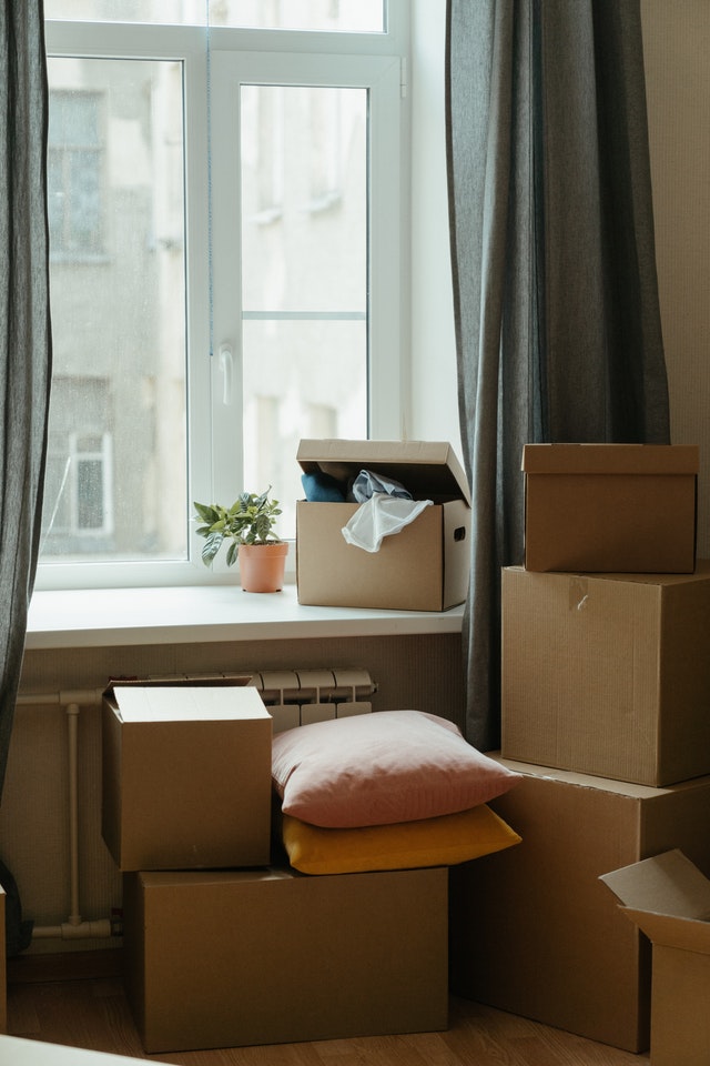 A bunch of boxes by the window in a home. 
