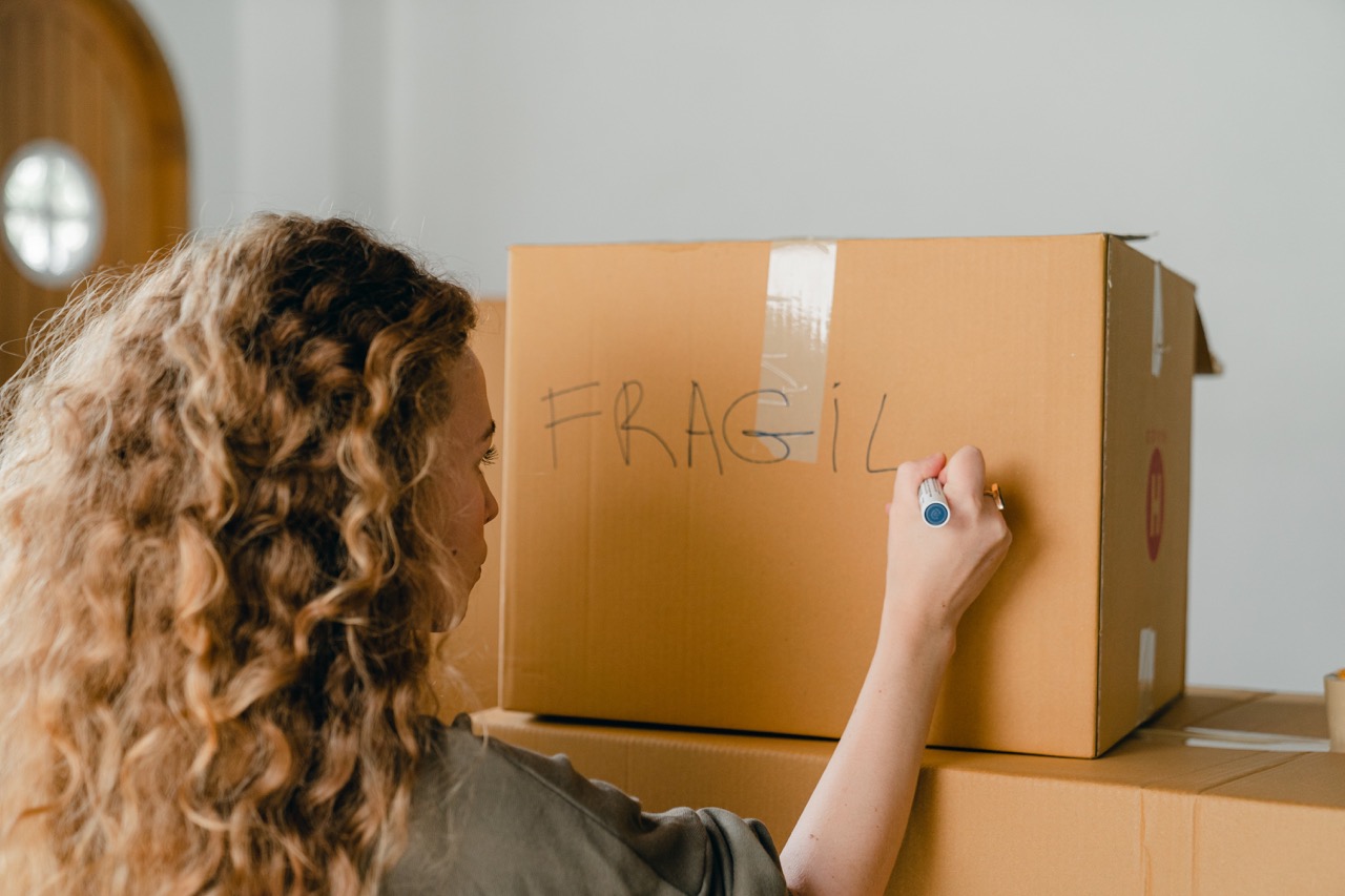 Woman labeling box of ornaments with "Fragile"