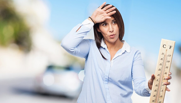 Woman with heat holding a large thermometer