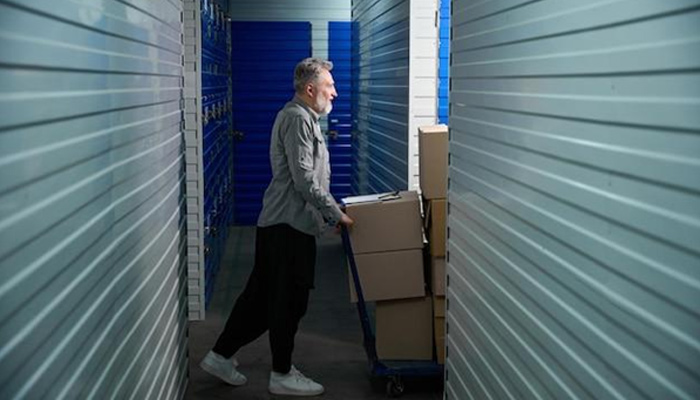 Man carrying storage cartons on a trolley to a self-storage facility.