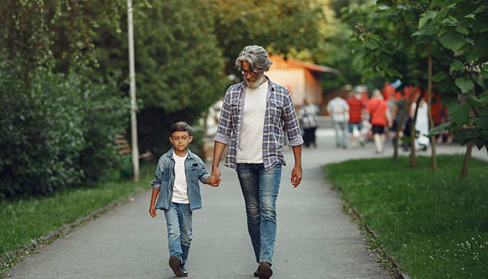 Boy and grandfather are walking in the park
