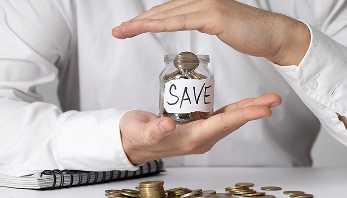 Person holding a 'SAVE' jar with coins