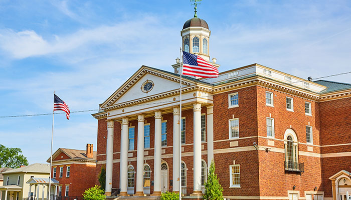 Red brick building with wind vane and American flags out front