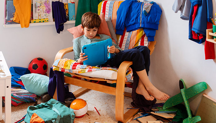 kid using his tablet in a messy room